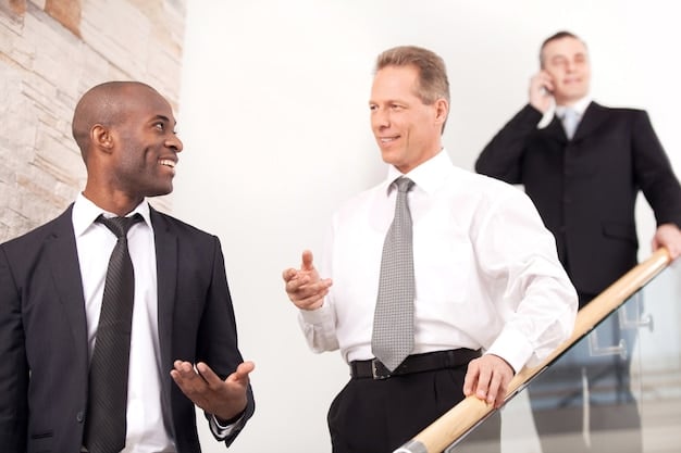 A businessman is standing in front of several people in business suits smiling and shaking his hand depicting a meeting and celebration of securing funds from investors