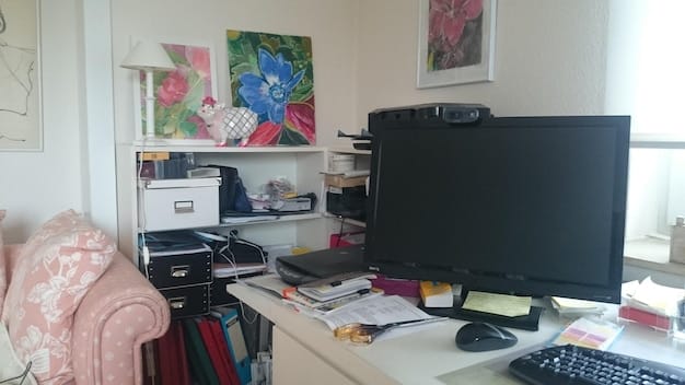 A well-organized home office setup with a dedicated desk, computer, ergonomic chair, and bookshelves filled with business-related resources. Natural light is entering through a window, creating a productive and comfortable workspace.