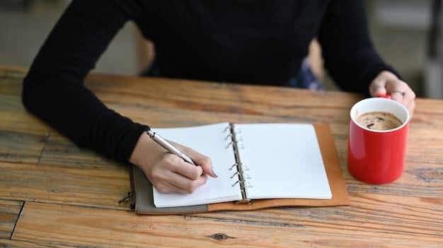 A close-up of a freelancer's hand writing down SMART goals in a notebook. The notebook has colorful sections labeled 