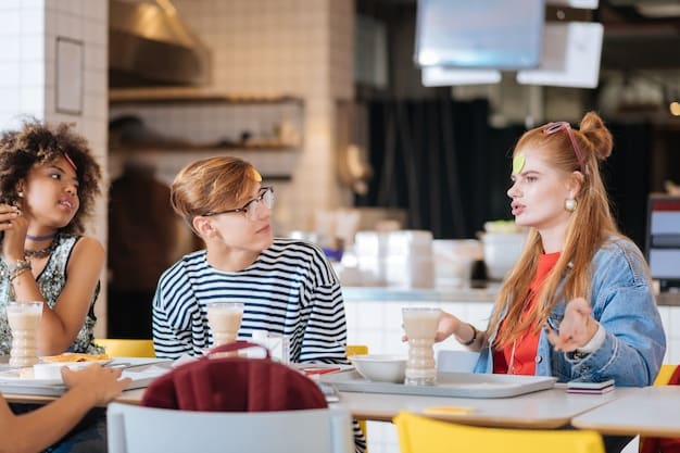 A student working part-time at a coffee shop, smiling and serving a customer. The background shows a busy cafe environment with other students studying.