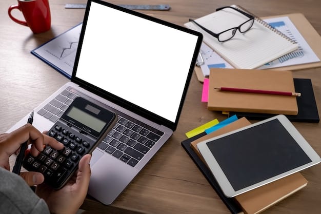 A person sitting at a desk with a laptop, calculator, and a notebook titled 