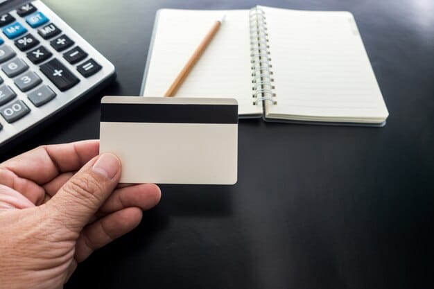 A close-up of a credit card statement showing a balance decreasing, with a hand holding a pen crossed out numbers. The image depicts disciplined financial management and debt reduction.