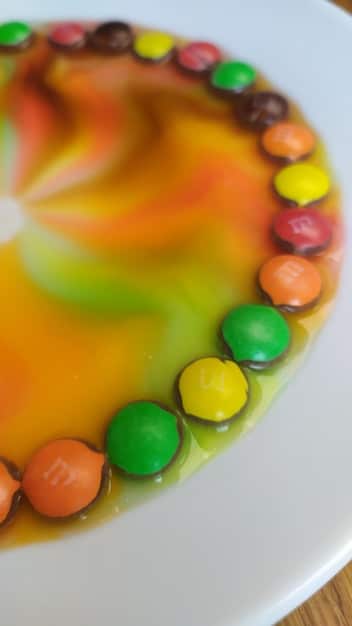 A close-up image of a vibrant, colorful, and artificially flavored candy, with an ingredient label showing a complex list of chemical names, highlighting the hidden additives in processed foods.