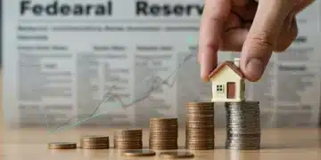 Hand placing miniature house on coin stack with financial charts, symbolizing Federal Reserve interest rate impact on mortgages.